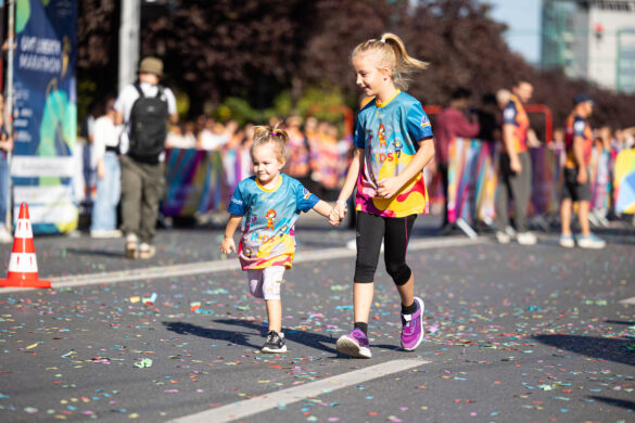 două fetițe în tricouri colorate aleargă de mână pe traseul UVT Liberty Marathon două fetițe în tricouri colorate aleargă de mână pe traseul UVT Liberty Marathon