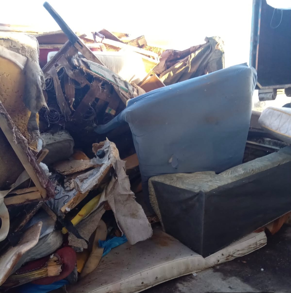 grămadă de mobilier și saltele vechi aruncate, încărcate într-o benă