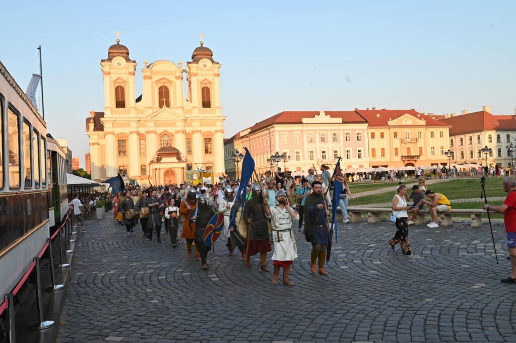 paradă medievală cu scuturi și steaguri în Piața Unirii din Timișoara, lângă catedrala romano-catolică