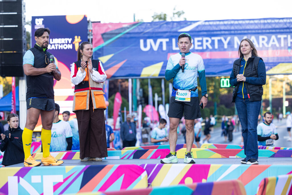 patru persoane pe scenă la startul UVT Liberty Marathon, bărbat vorbind la microfon